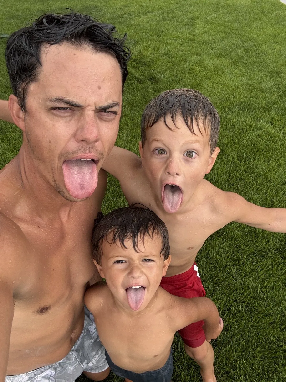 Andy and his two boys pulling faces on the lawn